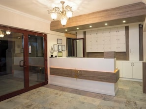 A reception area with a wooden reception desk, a chandelier, and a set of lockers in the background.