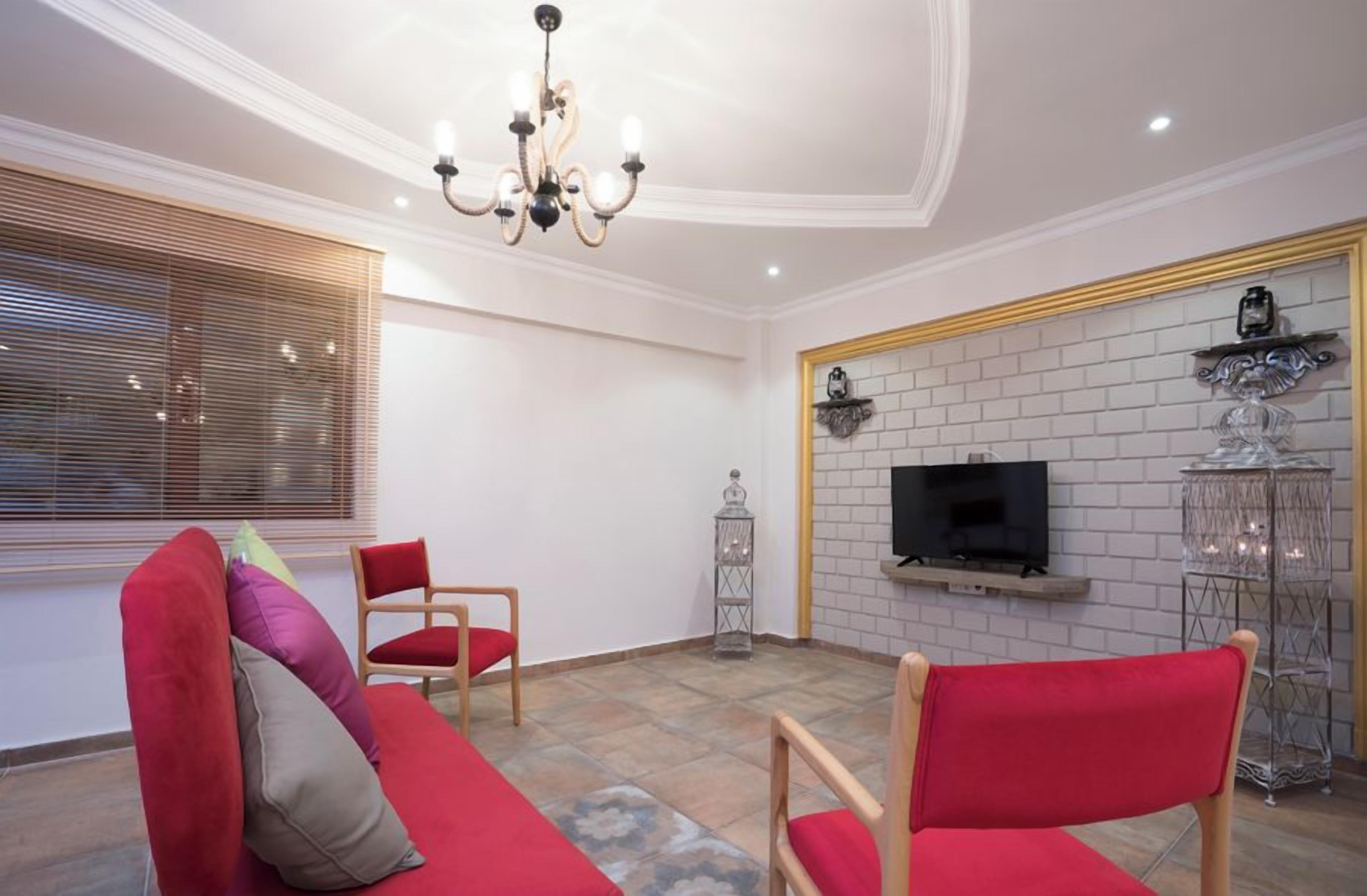 A living room with a sofa, chairs, a TV, and decorative items.