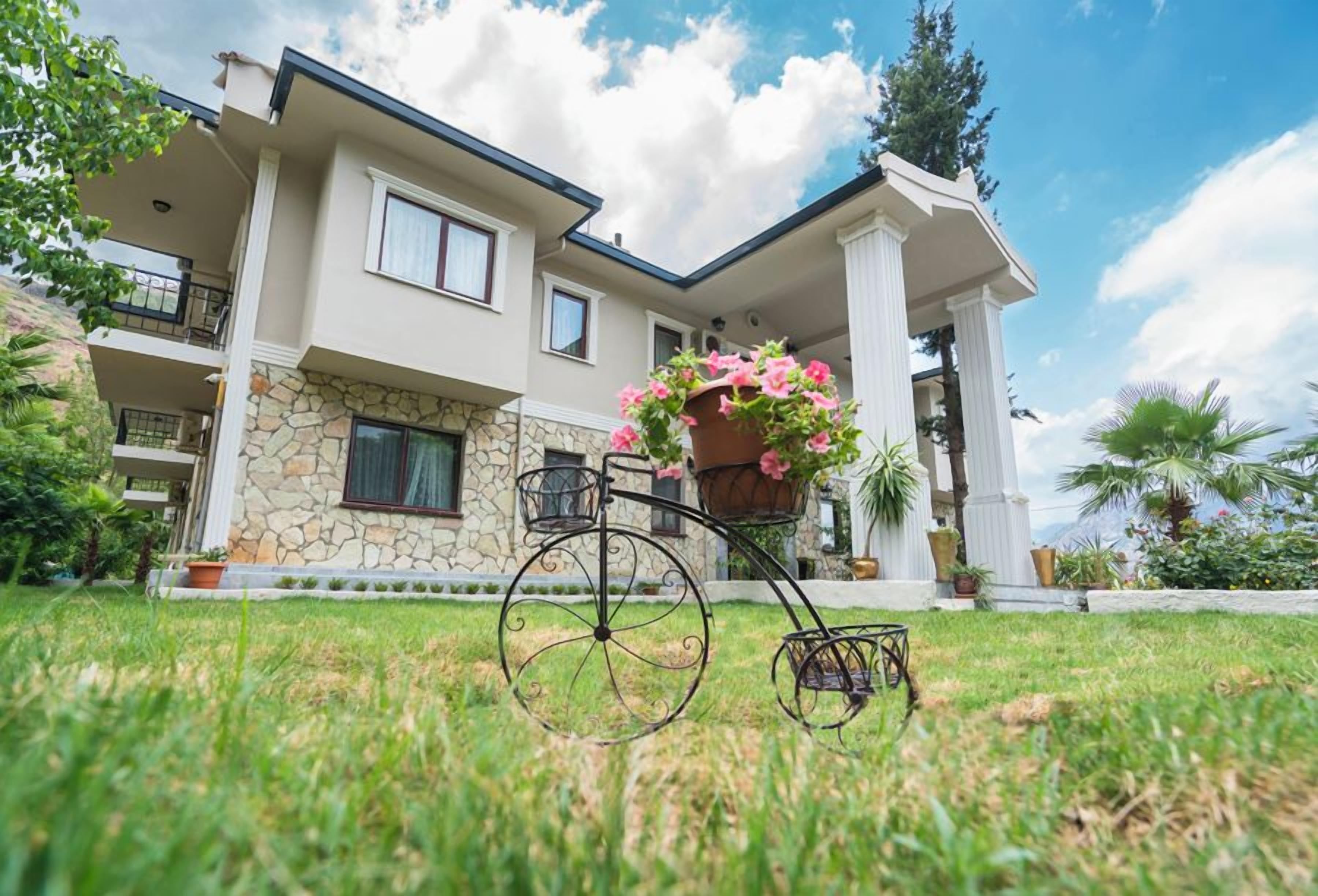 A two-story house with a stone facade, a balcony, and a bicycle with a flower basket.