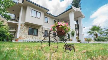 A two-story house with a stone facade, a balcony, and a bicycle with a flower basket.