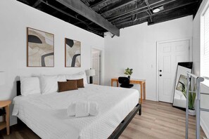 A modern bedroom with a large bed, a desk, and two abstract paintings on the wall. - The Neuschwanstein Flat- Walkable (Columbus)
