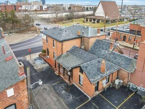 A multi-story brick building with a flat roof, a parking lot in front, and a stop sign nearby.