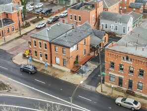A street view with a two-story brick building, a sidewalk, and parked cars.