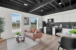 A modern kitchen with white cabinets, a black countertop, and a microwave. - The Neuschwanstein Flat- Walkable (Columbus)