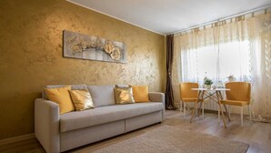 A living room with a sofa, two chairs, a coffee table, and a painting on the wall. - confortable accomodation in a safe area (București)