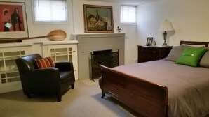 A bedroom with a bed, a chair, a fireplace, and artwork on the walls. - Entire basement apartment, Prime location! (Salt Lake City)