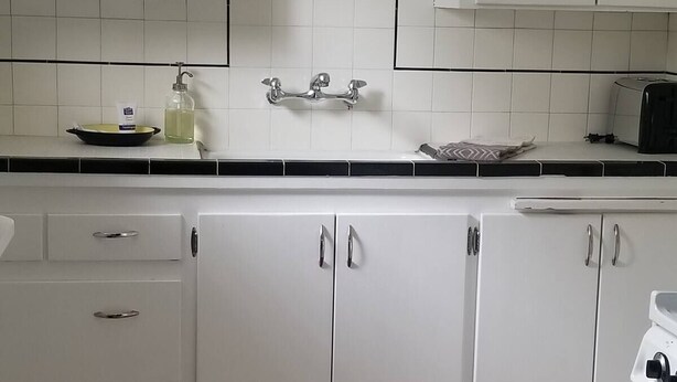 A kitchen with white cabinets, a black countertop, and a red patterned floor mat. - Entire basement apartment, Prime location! (Salt Lake City)