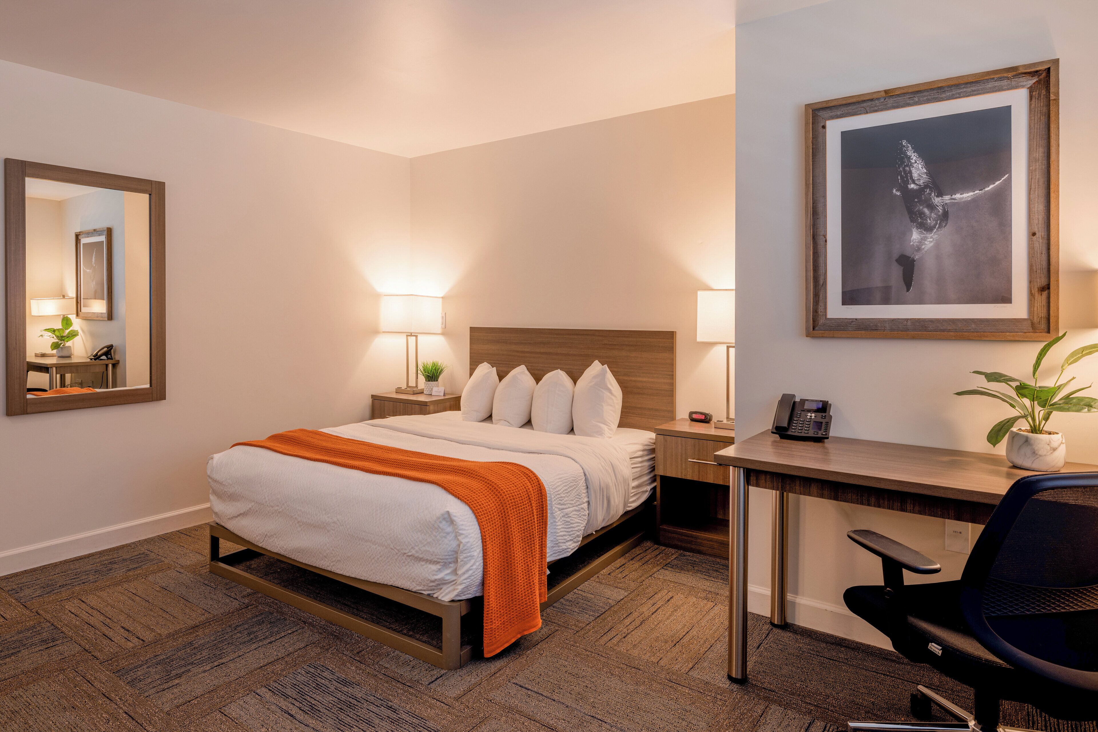 A hotel room with a bed, bedside tables, a desk, and a chair.