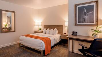 A hotel room with a bed, bedside tables, a desk, and a chair.
