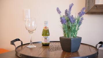 A round wooden table with a bottle of sparkling wine, a glass, and a potted lavender plant.