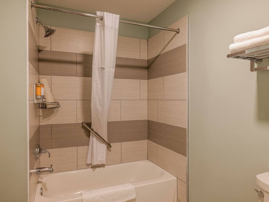 Un baño con bañera, cortina de ducha y toallero.