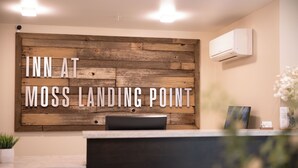 A reception desk with a wooden wall backdrop displaying the text "INN AT MOSS LANDING POINT". - Inn At Moss Landing Point (Moss Landing)