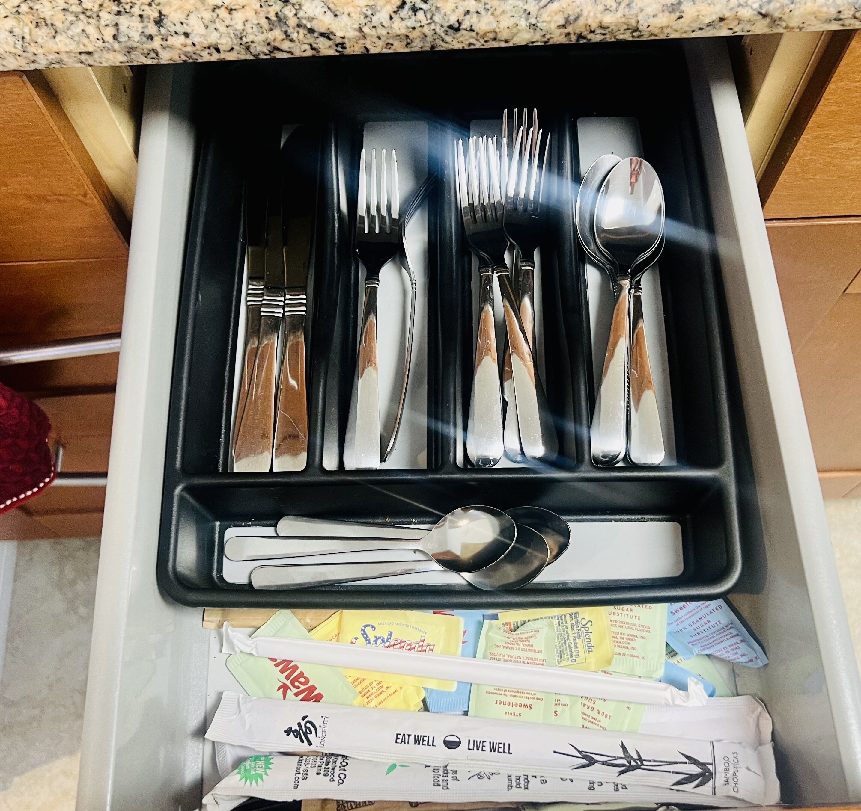 A drawer containing a set of silverware, including forks, knives, and spoons, neatly arranged.