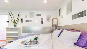 A modern bedroom with a bed, a bedside table, a potted plant, and a wall-mounted shelf. - Close to Siesta Key  beach with a hot tub  and a large  garden (Sarasota)