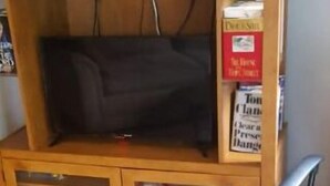 Een houten entertainmentkast met een televisie, speakers en boeken.