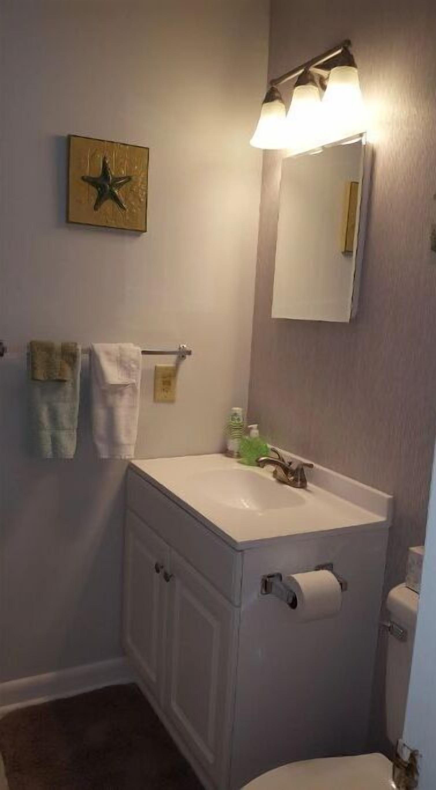 A bathroom with a white sink, a mirror, and a star decoration on the wall.