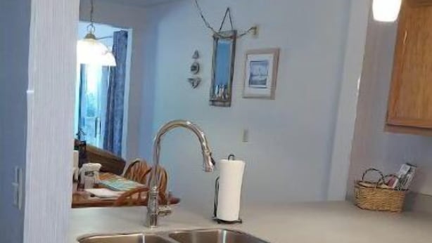 Een keuken met houten kastjes, een vaatwasser, een spoelbak en hangende lampen.