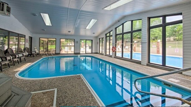 Une piscine intérieure offrant une vue dégagée sur l’extérieur, de grandes fenêtres et un plafond agrémenté de lucarnes.