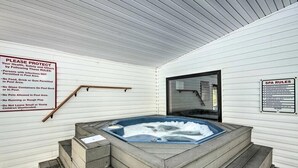 Un espace bien-être comprenant un bain à remous, des marches en bois et deux panneaux indiquant les règles et les consignes à respecter dans le spa.