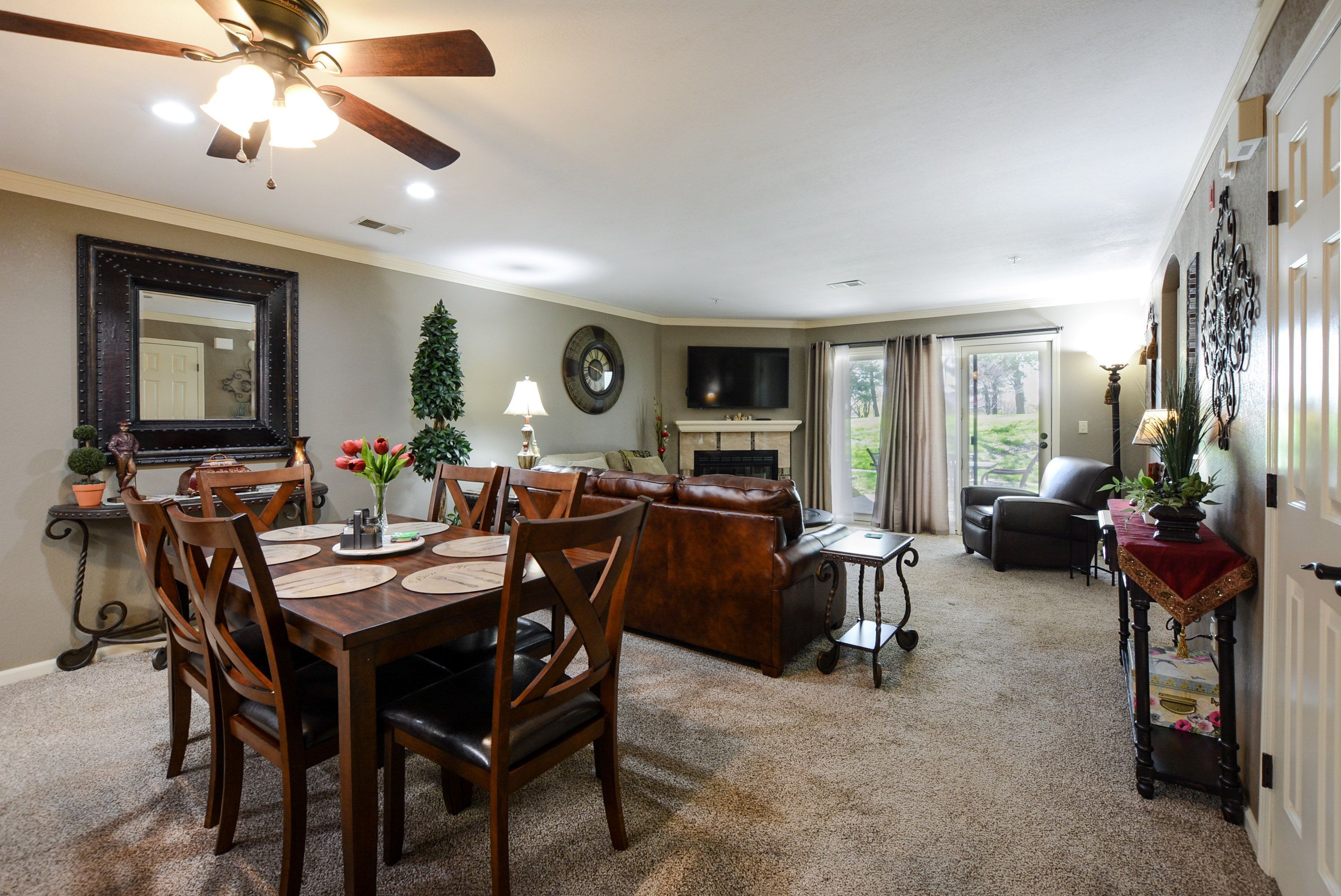 A dining area with a wooden table and chairs, a fireplace, and a television in the living room.