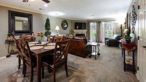 Un coin repas avec une table et des chaises en bois, une cheminée et un téléviseur dans le salon.