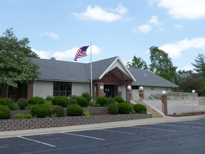 Stately building with a brick facade and gabled roof, set amidst a beautifully landscaped area.