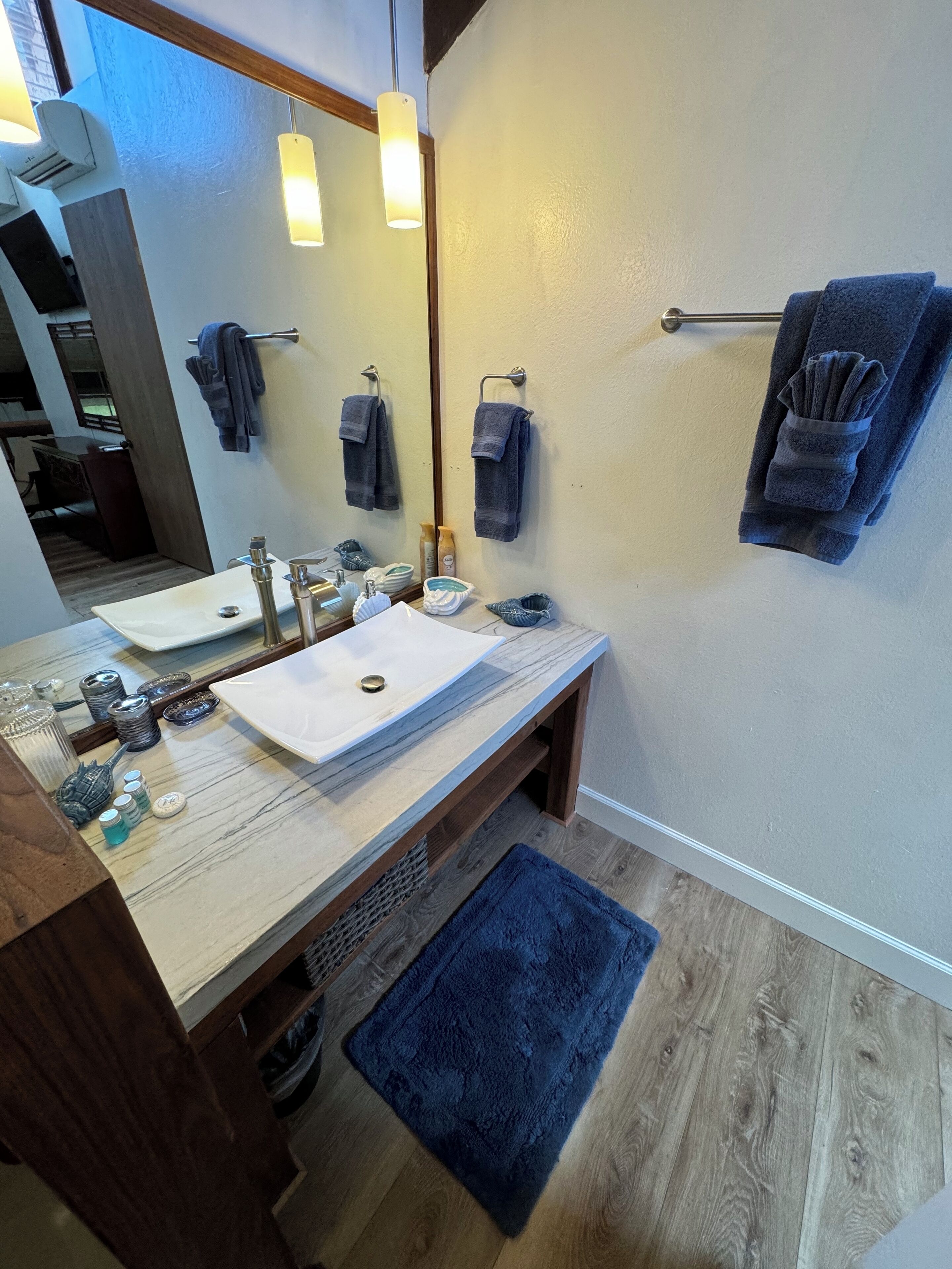 Un baño moderno con dos lavamanos, un espejo grande y toallas en un perchero.