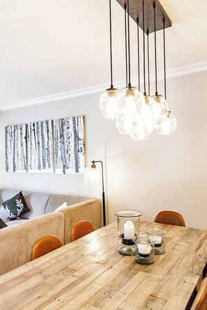En matplats med ett träbord, stolar och en hängande lampa.