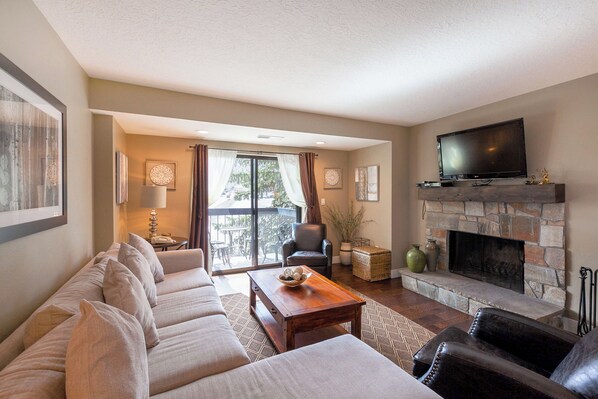 A spacious living room with a large sofa, a fireplace, and a television.