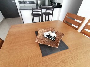 Enjoy meals in this dining area with a wooden table and chairs, featuring a modern kitchen in the background.