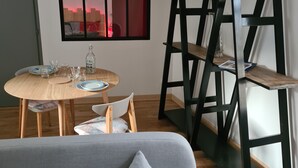 Una sala de estar moderna con un sofá gris, una mesa de comedor de madera y sillas de metal negro.