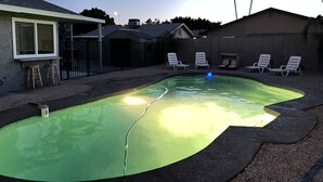 Un jardin avec une piscine, des chaises longues et un patio couvert.