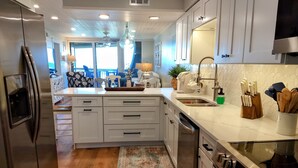 A modern kitchen with white cabinetry, stainless steel appliances, and a large island.
