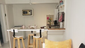 Un espace de vie compact comprenant un lit, une petite kitchenette et un coin repas.