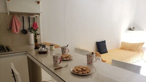 Une cuisine moderne avec un coin repas, un lit recouvert d’une couverture jaune et une petite table avec de la nourriture et des boissons.