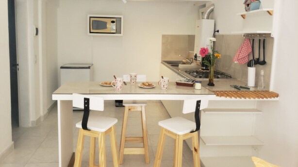 Une cuisine moderne dotée d’un îlot central, de deux tabourets, d’un four à micro-ondes et d’un évier.