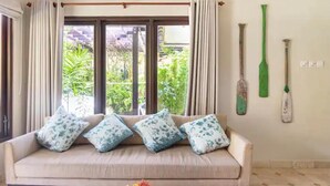 Ein Zimmer mit einer Couch, einem Fenster mit Vorhängen und einer Wand mit einem Fledermaus- und einem Cricket-Schläger.