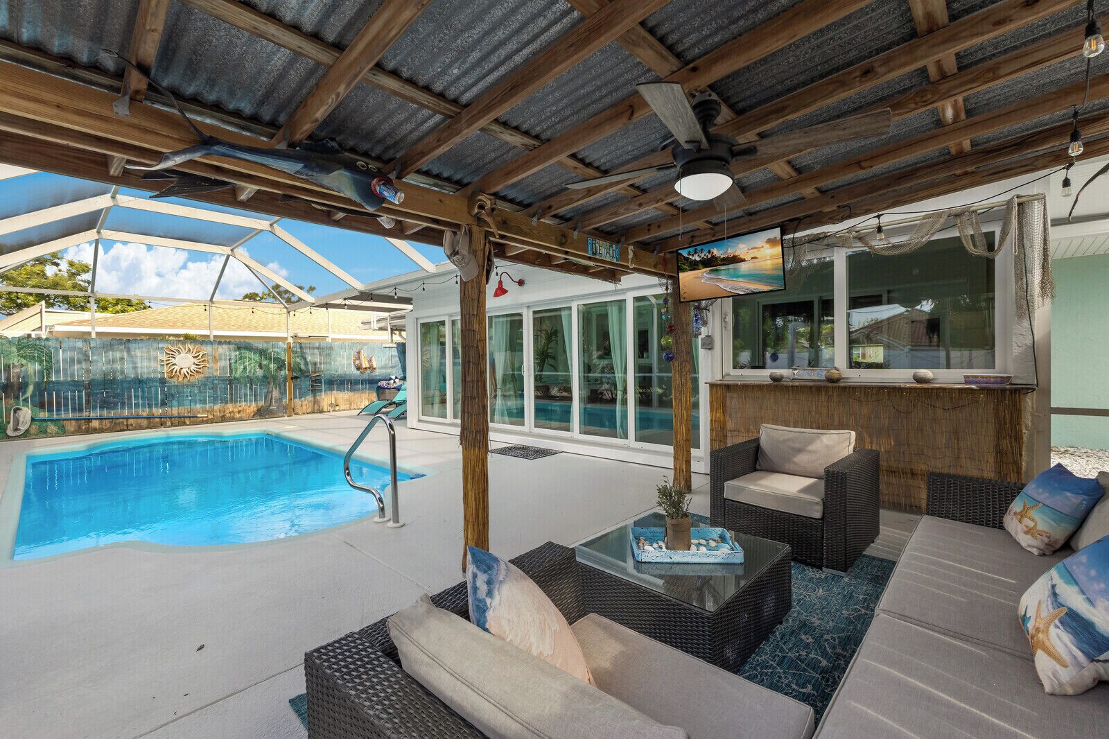 A covered outdoor area with a pool, wicker furniture, and a bar area.