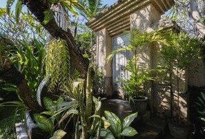 A courtyard with a stone building, potted plants, and a wooden door.