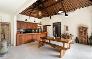 A spacious kitchen with wooden cabinets, a large island, pendant lights, and a traditional ceiling.