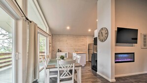 Una cocina moderna con televisor integrado, chimenea y zona de comedor con mobiliario blanco.