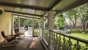 Une véranda avec une chaise berçante et vue sur un jardin.