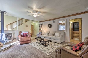 Cozy living room with a fireplace, leather armchairs, and a sofa, featuring a staircase and bookshelf.