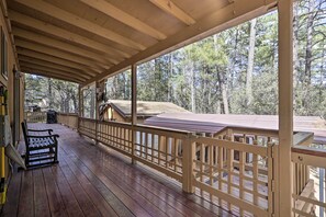 Guests can enjoy a safe and comfortable space on the covered deck, surrounded by a serene forest environment.