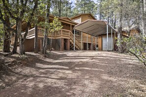 Escape to a serene forest setting, surrounded by nature, with a covered porch and staircase leading to an upper level.