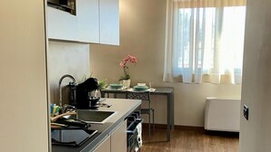 Cocina pequeña con lavamanos, cocina y mesa de comedor.