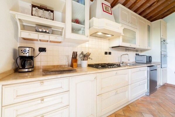 Una cocina con armarios blancos, cafetera, tostadora y lavavajillas.