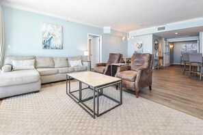 Ein Wohnzimmer mit Sofa, Sesseln, einem Couchtisch und einem Essbereich mit Stühlen und Tisch.