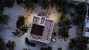 An aerial view of a building with a flat roof, surrounded by palm trees. - Permit- Beachfront Apartment (6 guests), Level 1 (Xcalak)