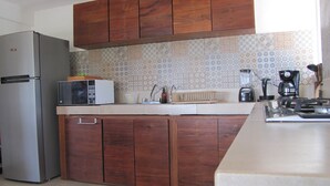 A kitchen with wooden cabinets, a refrigerator, a microwave, a sink, and a coffee maker. - Permit- Beachfront Apartment (6 guests), Level 1 (Xcalak)